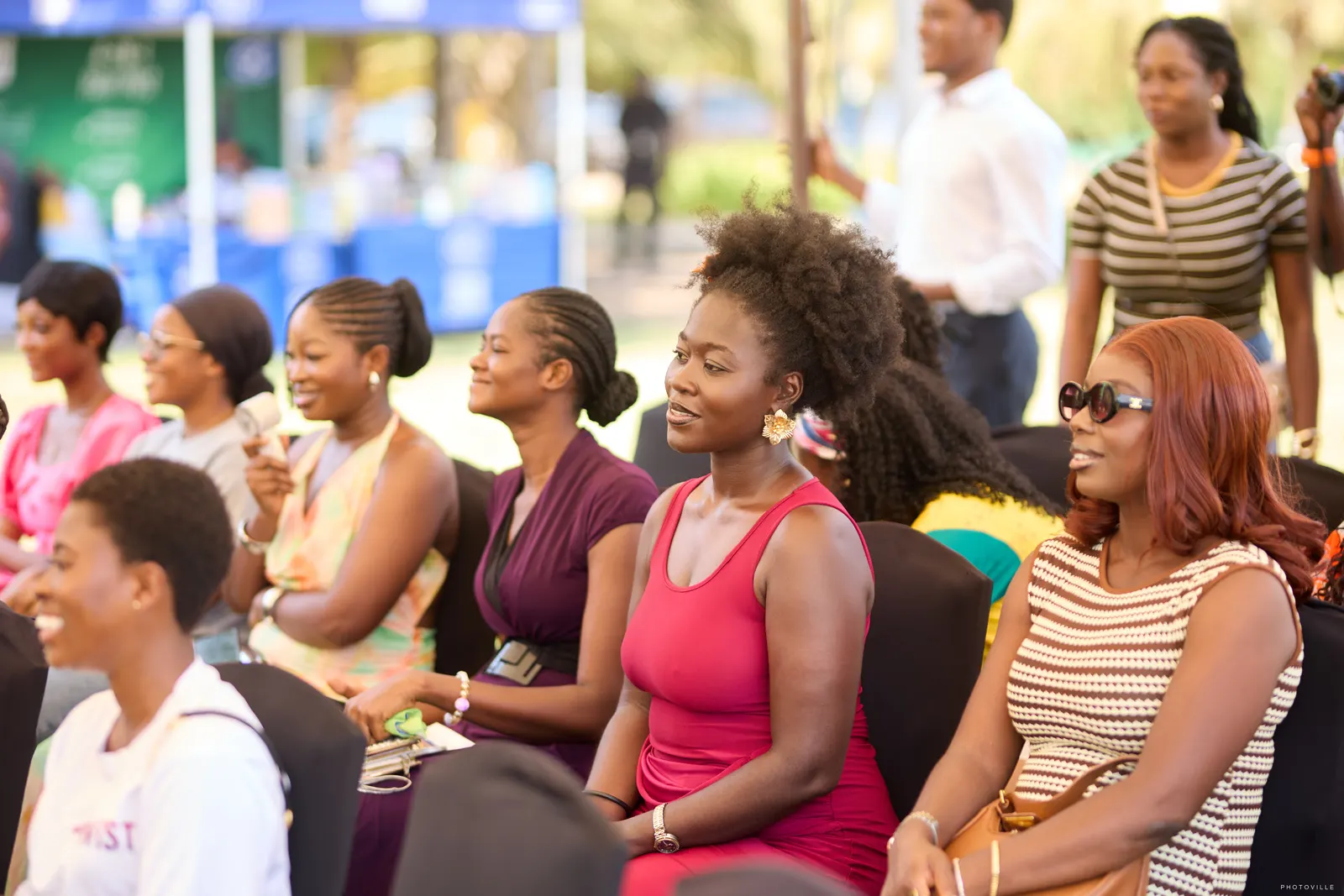 Smiling guests seated in rows enjoying an outdoor daytime session