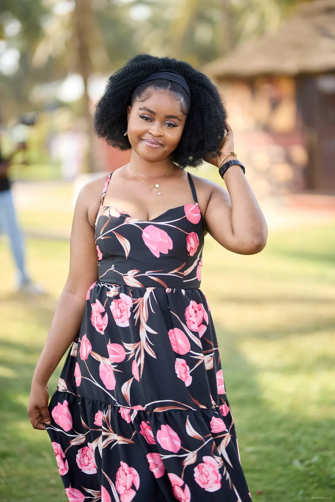 Smiling woman in a black floral maxi dress with natural hair on a garden lawn
