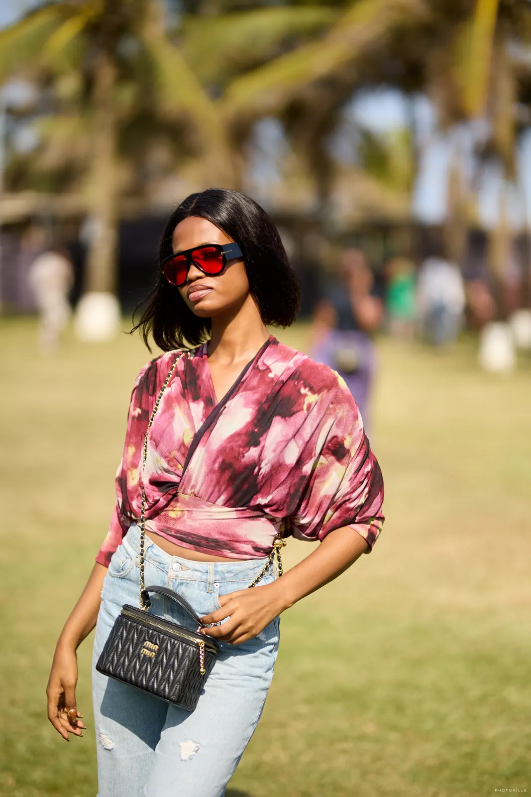 Woman in a pink tie-dye top and red sunglasses on a sunny lawn