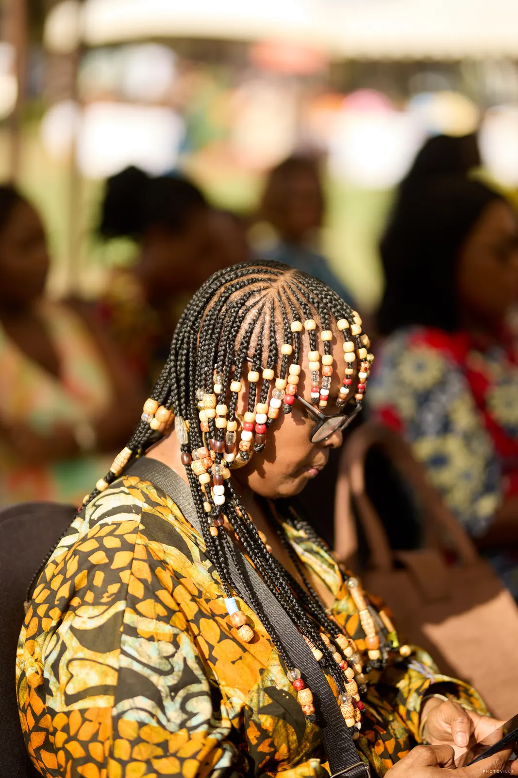 Close-up of beaded braids on a guest in an orange and black print outfit