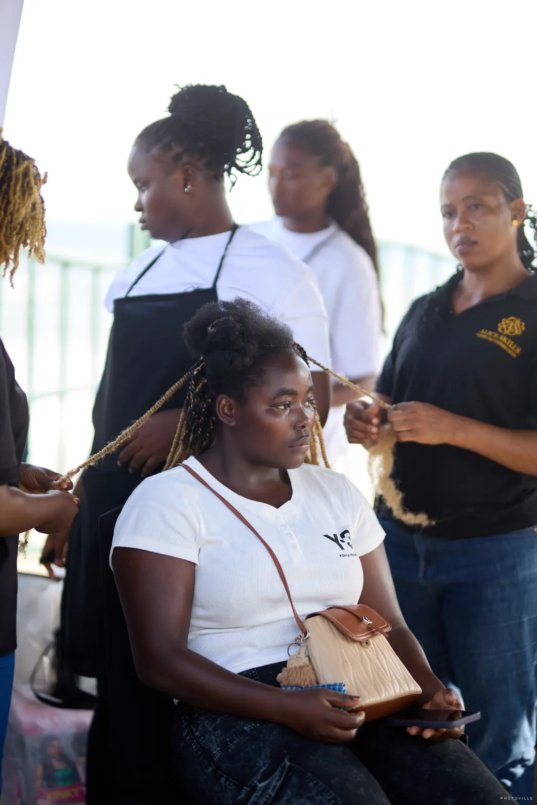 Stylists braiding a seated guest's hair at an outdoor station