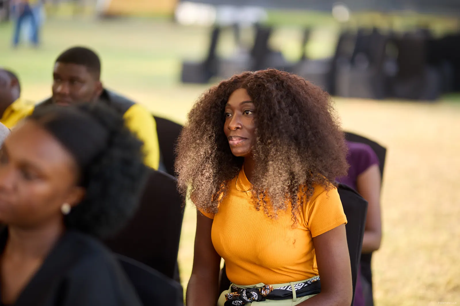 Woman in a yellow top with voluminous curly hair seated in the audience