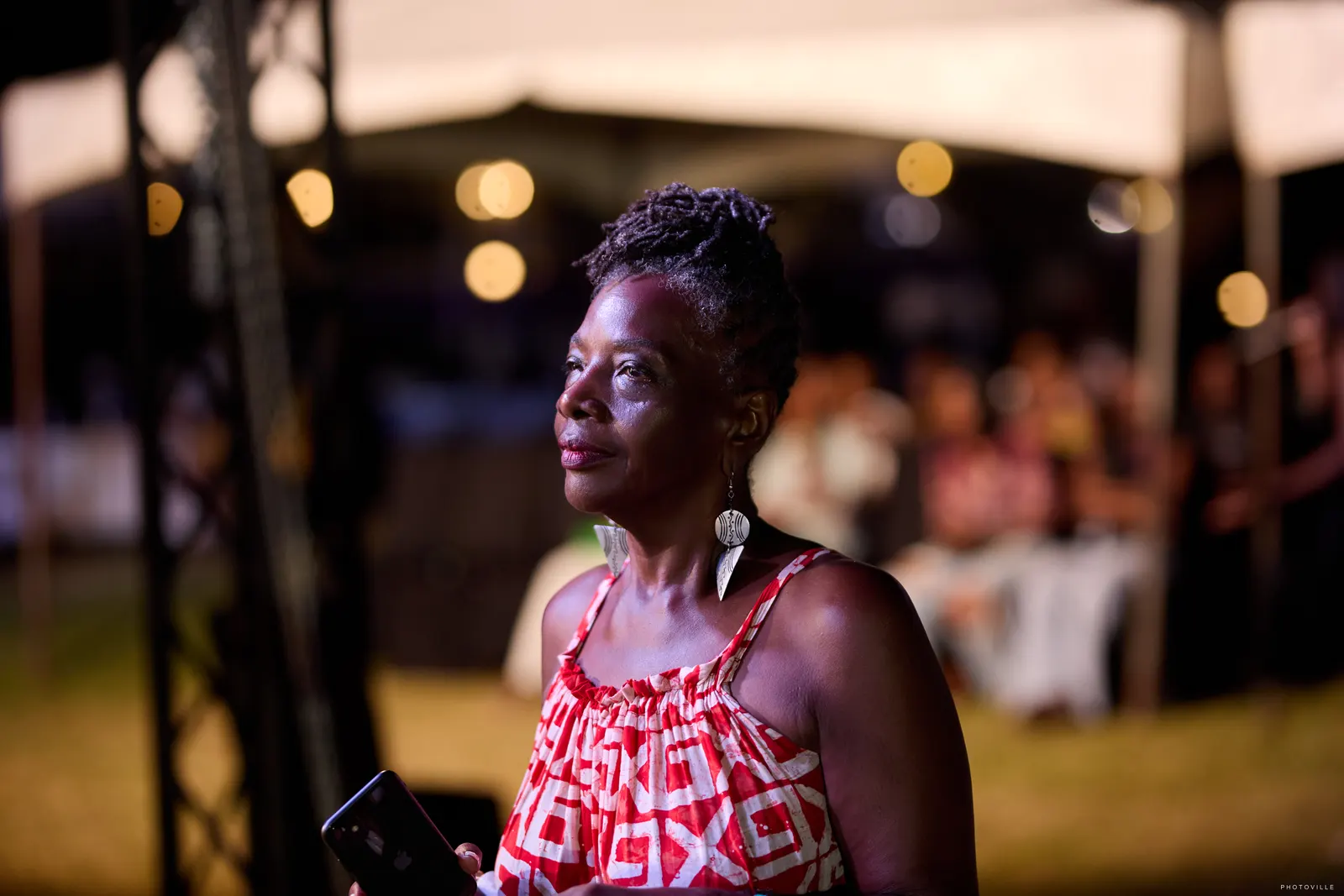 Woman in a red and white print top in soft evening light under string lights