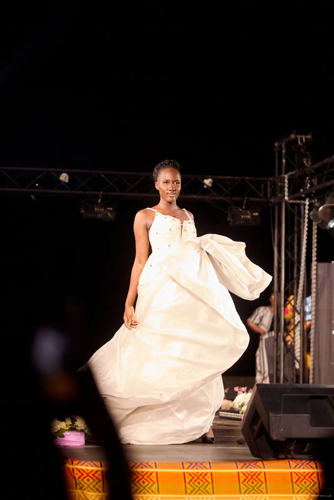 Model in a flowing white gown with dramatic train on the runway